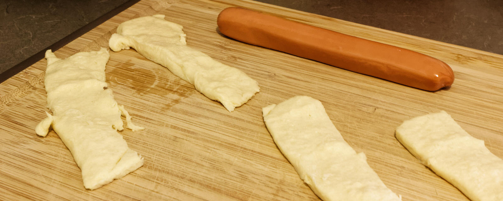 Pillsbury Crescent stripes with sausage Pillsbury Crescent stripes on a cutting board with a wiener sausage